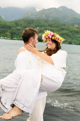 COUPLE PHOTOSHOOT IN TAHITI ON A DARK SAND BEACH WITH MOUNTAIN VIEW AND FLOWER CROWN